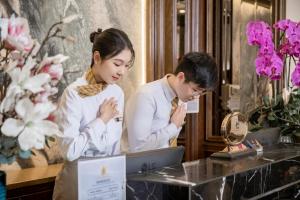 um homem e uma mulher olhando para um laptop em Minasi Premium Hotel em Hanói