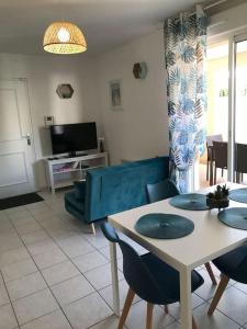 ein Wohnzimmer mit einem Tisch, Stühlen und einem Sofa in der Unterkunft Appartement idéalement situé - la Seyne sur mer in La Seyne-sur-Mer