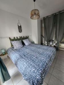 Schlafzimmer mit einem Bett mit blauer Decke in der Unterkunft Appartement idéalement situé - la Seyne sur mer in La Seyne-sur-Mer
