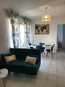 ein Wohnzimmer mit einem grünen Sofa und einem Tisch in der Unterkunft Appartement idéalement situé - la Seyne sur mer in La Seyne-sur-Mer