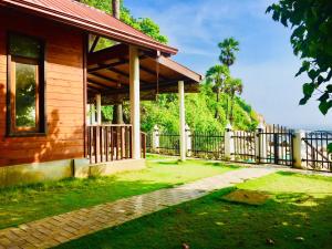 a wooden house with a fence next to a yard at Janas Blue Water Corner in Trincomalee