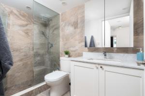 a bathroom with a toilet and a glass shower at Stunning 2BR + 2.5BA Luxury Townhome Steps from Square One! in Mississauga