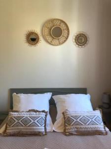 a bed with two pillows and two mirrors on the wall at Hôtel Restaurant Les Chasseurs in Marine de Pietracorbara