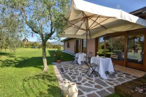 un patio con 2 mesas y una sombrilla en Agriturismo le Orchidee di Corazza en Picedo