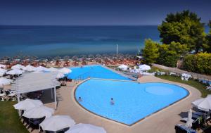 an overhead view of a swimming pool with umbrellas and the ocean at Istion Club & Spa in Nea Potidaea