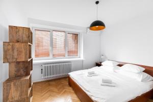 a white bedroom with a bed and two windows at P&O Apartments Powiśle in Warsaw