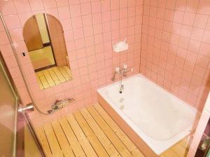 a pink tiled bathroom with a tub and a mirror at 稲荷 かおり in Kyoto