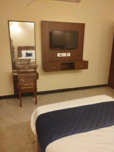 Habitación de hotel con TV y espejo. en A.R Residency, en Chennai