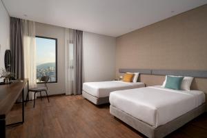 a hotel room with two beds and a desk at Em Oi Boutique Hotel in Nha Trang