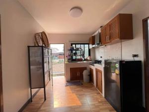 a kitchen with a black refrigerator and wooden floors at บ้านกลางนาพูลวิลล่า in Nan