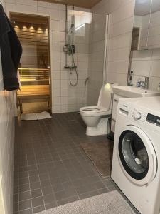 a bathroom with a toilet and a washing machine at Modern city apartment with Sauna nearby the Airport in Vantaa