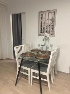 a dining room table with four chairs and a glass table at Modern city apartment with Sauna nearby the Airport in Vantaa