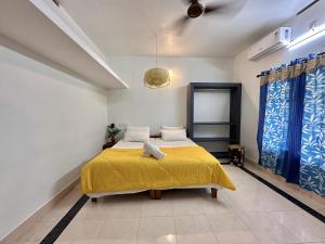 1 dormitorio con 1 cama con colcha amarilla en Varkala Villa, en Varkala