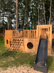 a wooden play house with a slide in the grass at Villa Norda Dębki in Dębki