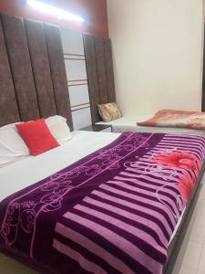 a bedroom with two beds with a purple and white blanket at Hotel Jyoti Deluxe in New Delhi