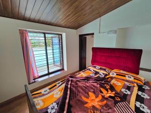 a bedroom with a bed with a colorful comforter and a window at Yaal Homestay in Kodaikānāl