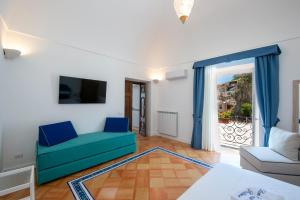 a living room with a blue couch and a tv at Casa Don Ciccio Positano in Positano