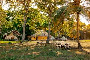 a park with tents and a bench and palm trees at Cabañas Tequendama Playa Arrecifes Parque Tayrona in El Zaino