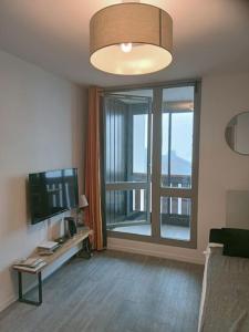 een woonkamer met een televisie en een groot raam bij Val Thorens Studio 2 personnes et balcon Plein Sud in Val Thorens