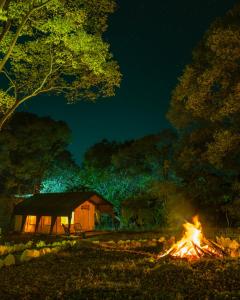 a bonfire in front of a cabin at night at H2H Bir l Nature Camps in Bīr