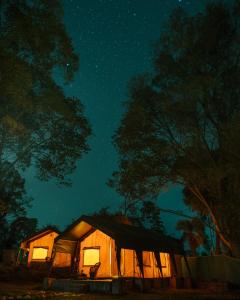 a tent is lit up at night under the stars at H2H Bir l Nature Camps in Bīr