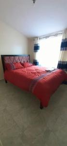 un grande letto rosso in una stanza con finestra di Dennis Prince pm comfy home a Nairobi