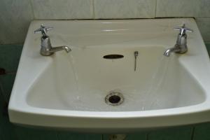 un lavandino bianco con due rubinetti in bagno di Dennis Prince pm comfy home a Nairobi