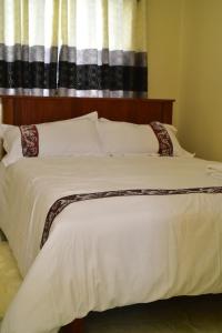 un letto con lenzuola e cuscini bianchi in una camera da letto di Dennis Prince pm comfy home a Nairobi