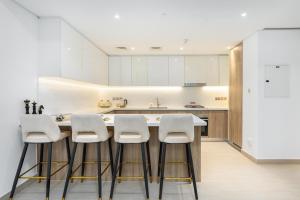 a kitchen with white cabinets and white stools at ArbabHomes Lavish 2BR Dubai Marina View-LIV Residences in Dubai
