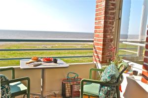 a table and chairs on a balcony with a view of the ocean at Le Continental in Cayeux-sur-Mer
