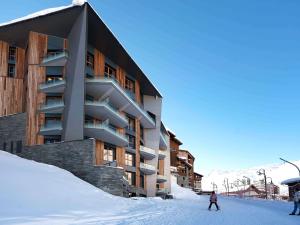 une personne à skis dans la neige devant un bâtiment dans l'établissement Hôtel Le Diamond Rock, à Tignes