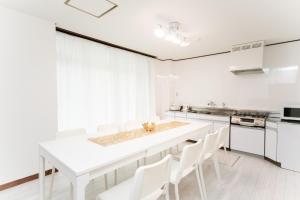 uma cozinha branca com uma mesa branca e cadeiras brancas em 菰野ガーデンリゾート 