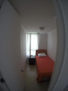 Un pequeño dormitorio con una cama roja y una ventana en Apartamento la serena, en Coquimbo