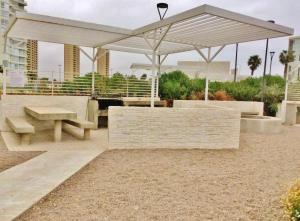 a picnic area with a white umbrella and benches at Apartamento la serena in Coquimbo