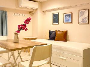 Un dormitorio con una cama y una mesa con un jarrón de flores en Dolce Shibuya en Tokio