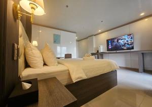 THE TIMES HOTEL في انجلس: غرفة نوم مع سرير كبير وتلفزيون على الحائط