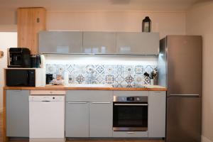 una cucina con armadi bianchi e frigorifero in acciaio inossidabile di Chez Rose - Plein Centre Historique a Langres