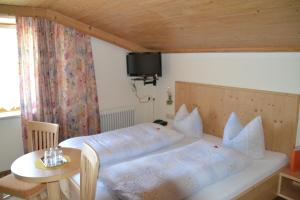a bedroom with two beds and a table and a tv at Haus Binder in Ried im Zillertal