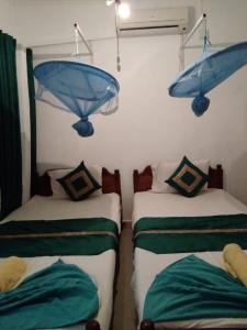two beds in a room with blue umbrellas on the wall at Rock Cascade tourist home in Polonnaruwa
