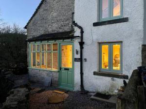 a house with a green door and two windows at Stunningly stylish cottage. in Bradwell