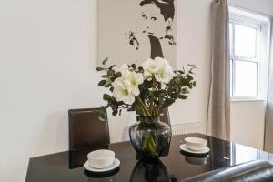 a vase filled with white flowers on a table at GRANGE City 2 Bed Modern Apartment by Tower Bridge London Bridge in London