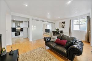 a living room with a leather couch and a kitchen at GRANGE City 2 Bed Modern Apartment by Tower Bridge London Bridge in London