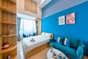 ein blaues Zimmer mit einem Bett und einem Sofa in der Unterkunft REM Rivergate Garden Pool Signature - Free 4G sim for 3 Nights Booking in Ho-Chi-Minh-Stadt