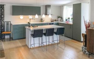 a kitchen with green cabinets and a island with bar stools at Lovely Apartment In Kattem With Sauna in Lund