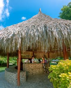 two people sitting at a bar under a straw umbrella at Camping Tequendama - Parque Tayrona in El Zaino