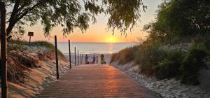 - un groupe de personnes marchant sur une plage au coucher du soleil dans l'établissement Apartament przy morzu W22, à Rowy