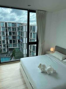 um quarto com uma cama branca e uma grande janela em Luxury condo in phuket shopping center em Phuket