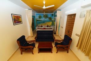 - un salon avec un lit et deux chaises dans l'établissement Pearl bell Villa, à Pondichéry