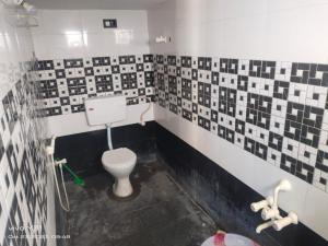 a bathroom with a toilet and tiles on the wall at BHARATH VILLAS in Vāniyambādi