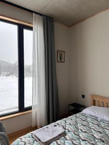 a bedroom with a bed and a window with snow outside at Bakuriani 44 in Bakuriani